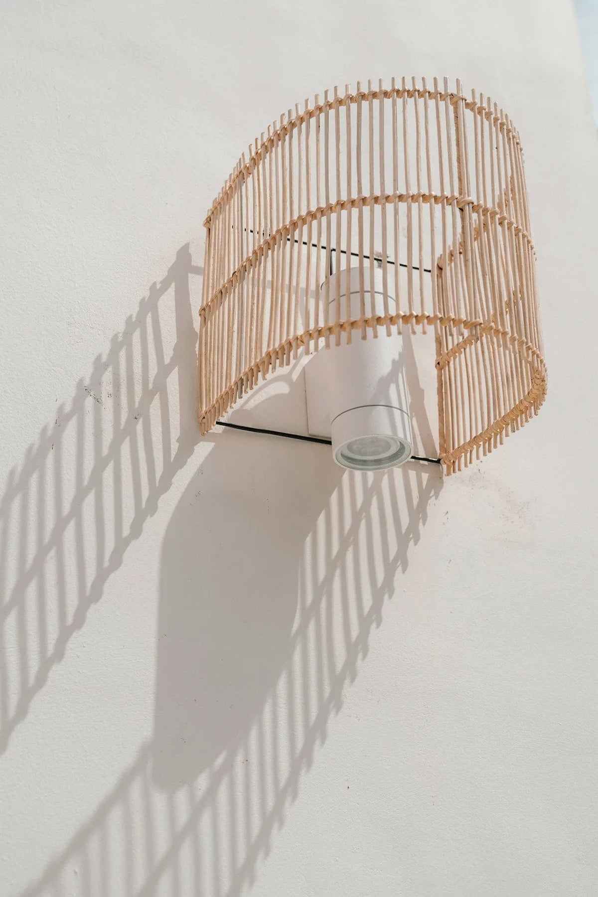 Gigi Rattan Wall Applique – Natural, Small – wall-mounted view casting a curved rattan shadow
