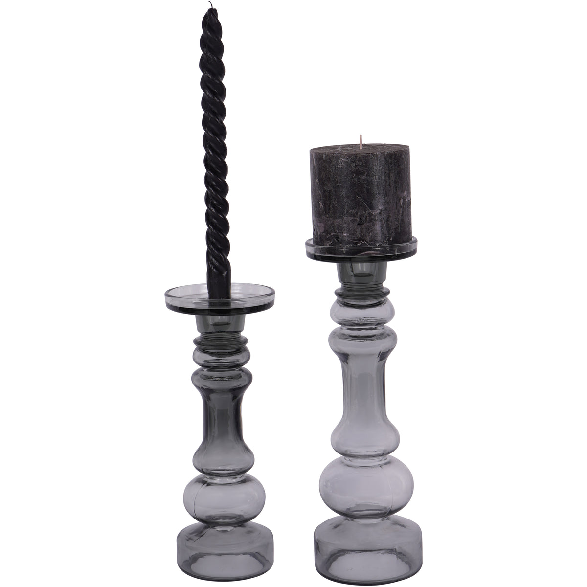 Two smoky grey glass candle holders, with a dark pillar candle on the larger holder at right and a twisted candle on the smaller holder at left.