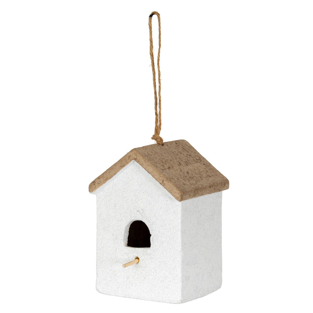 Three-quarter view of an off-white birdhouse-shaped ornament with a brown pitched roof, arched opening, pale perch and long tan rope loop.