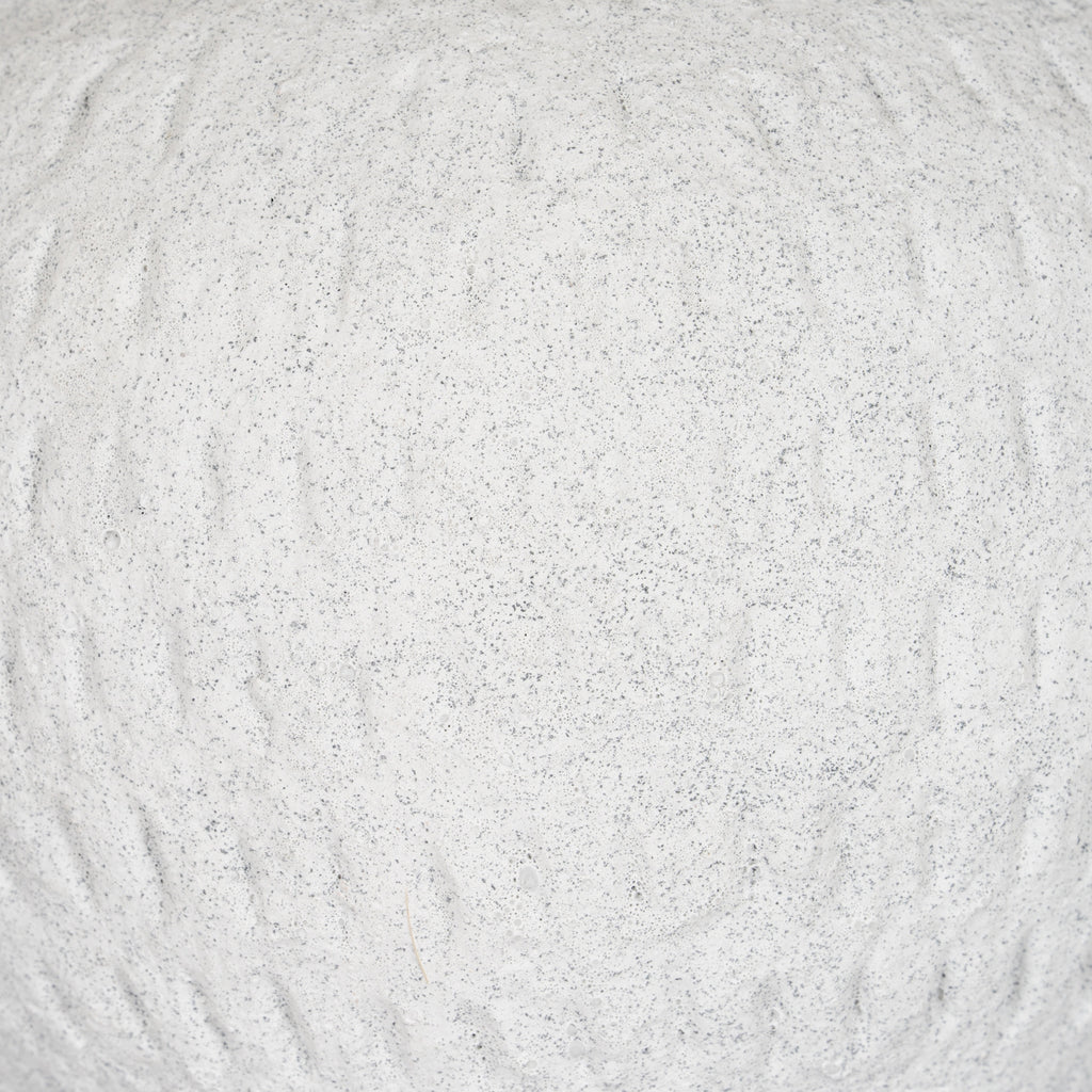Detail of the vase's pale granular surface, with fine grey speckles and irregular shallow vertical strokes.