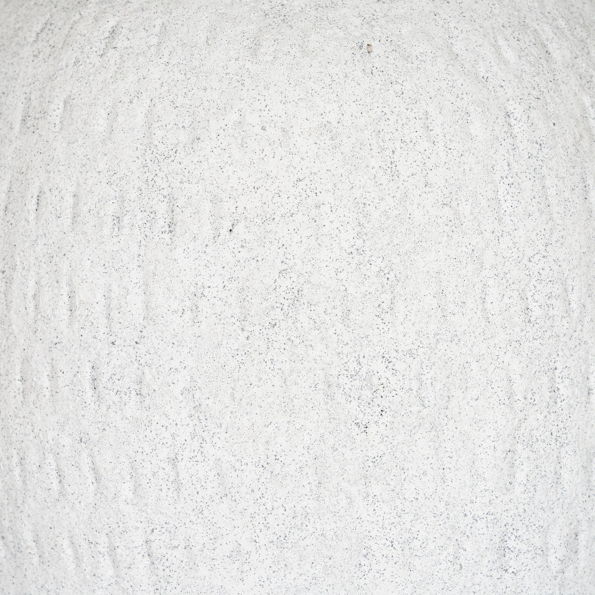 Detail of the vase's granular off-white surface with fine grey speckles and irregular shallow vertical strokes.