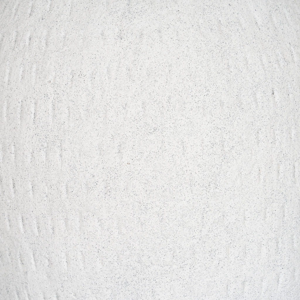 Close-up of the off-white granular surface, with fine grey flecks and irregular shallow vertical grooves.