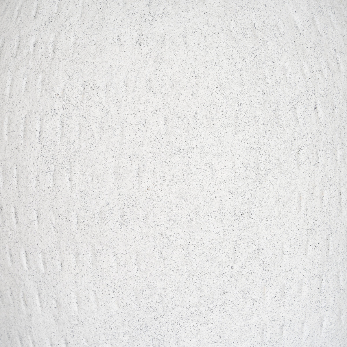 Close-up of the off-white granular surface, with fine grey flecks and irregular shallow vertical grooves.