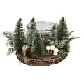 Green decorative wreath photographed around a reflective central vessel, with upright tree forms, white-tipped greenery, brown cone-shaped accents and cream berry-like details.