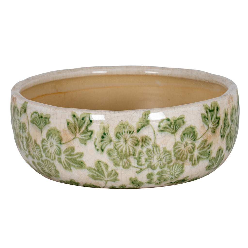 Shallow round planter with green flowers and leaves on a cream crackle finish, viewed from above to show the tan interior.