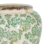 Close-up of green floral motifs across the curved vase shoulder, showing fine crackle lines, tan marks and glossy highlights beneath the distressed rim.