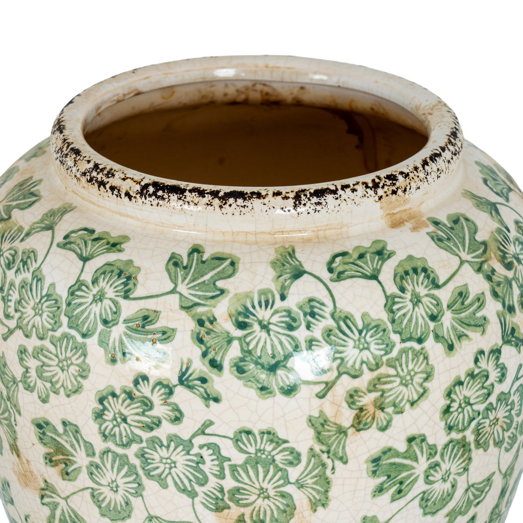 View into the vase opening, with a raised cream-white rim edged in dark distressed marks above the green floral pattern.