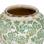 View into the vase opening, with a raised cream-white rim edged in dark distressed marks above the green floral pattern.