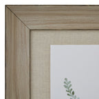 Close-up of the frame's upper left mitred corner, showing brown grain-like markings beside the finely textured beige surround.