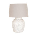 Table lamp against a white background, with a broad tapered beige shade above a rounded cream-toned base patterned with pale grey flowers, curling stems and faint crackle-like lines.