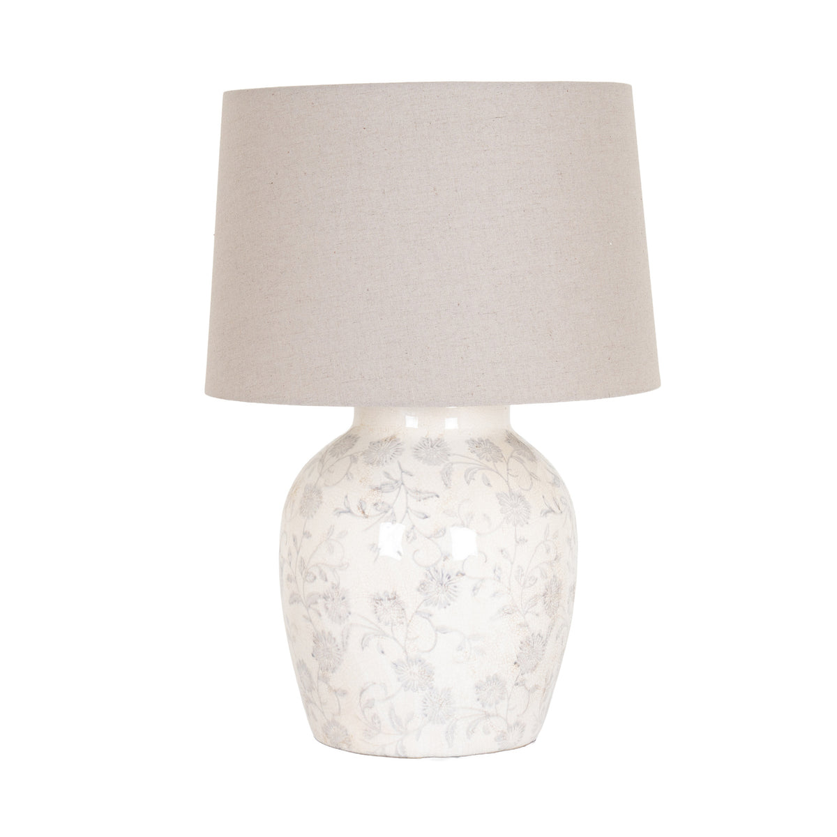 Table lamp against a white background, with a broad tapered beige shade above a rounded cream-toned base patterned with pale grey flowers, curling stems and faint crackle-like lines.