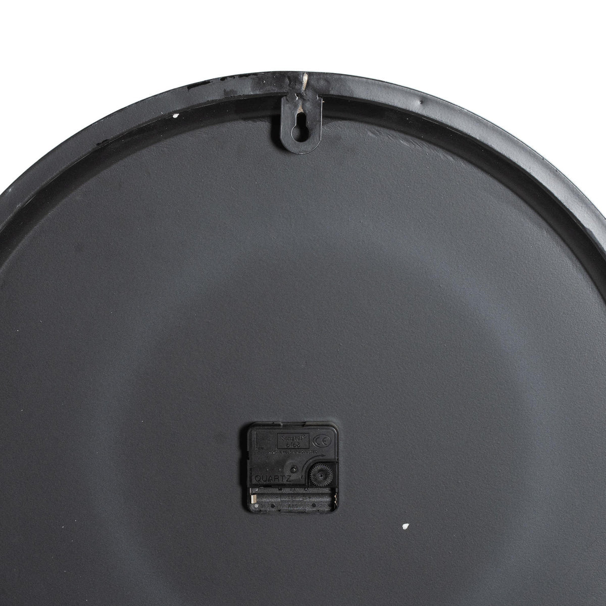 Rear view of the clock showing its dark circular back, central black movement and keyhole-shaped hanging tab at the top.