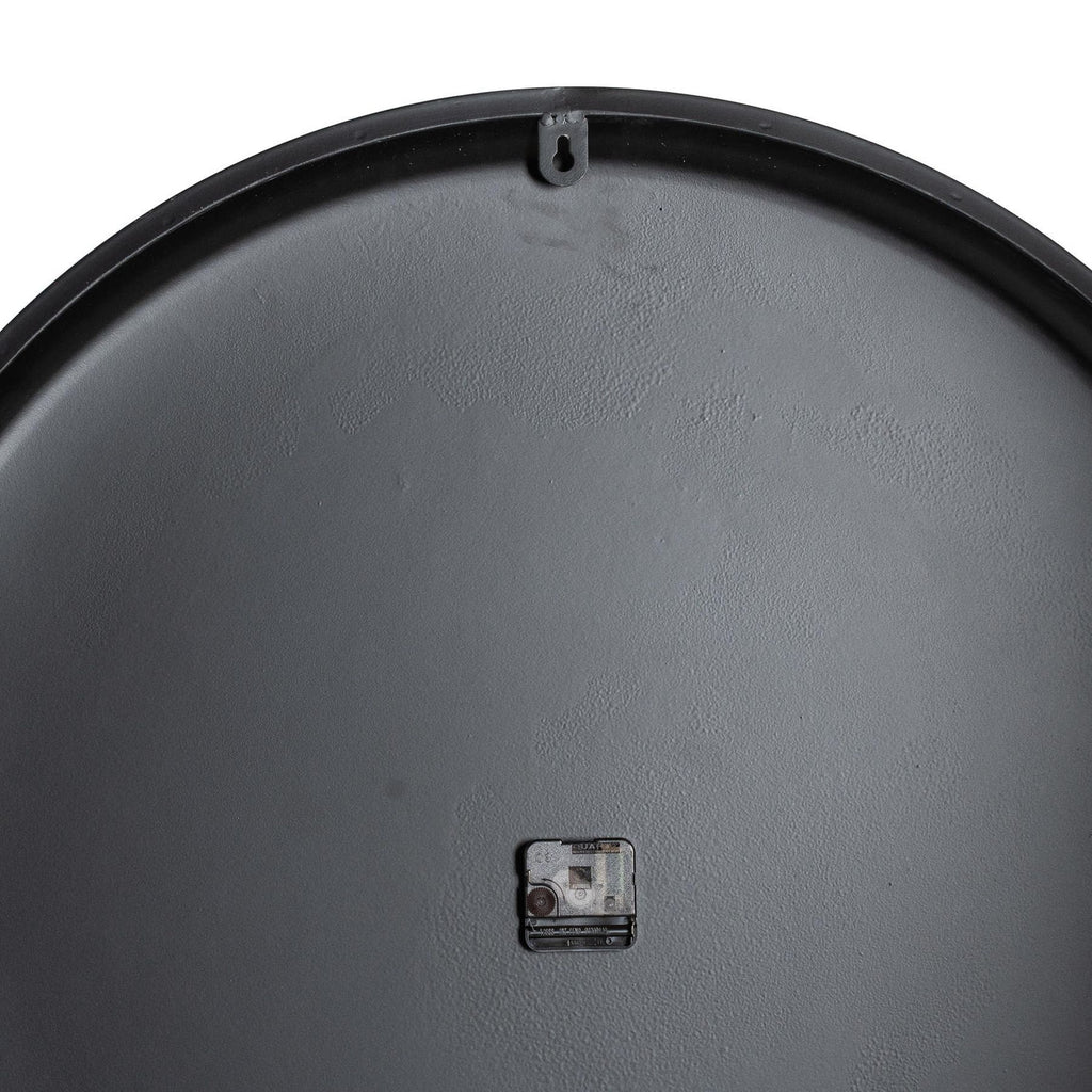Rear view of the clock showing its dark circular back, small central movement and keyhole-shaped hanging tab near the top rim.