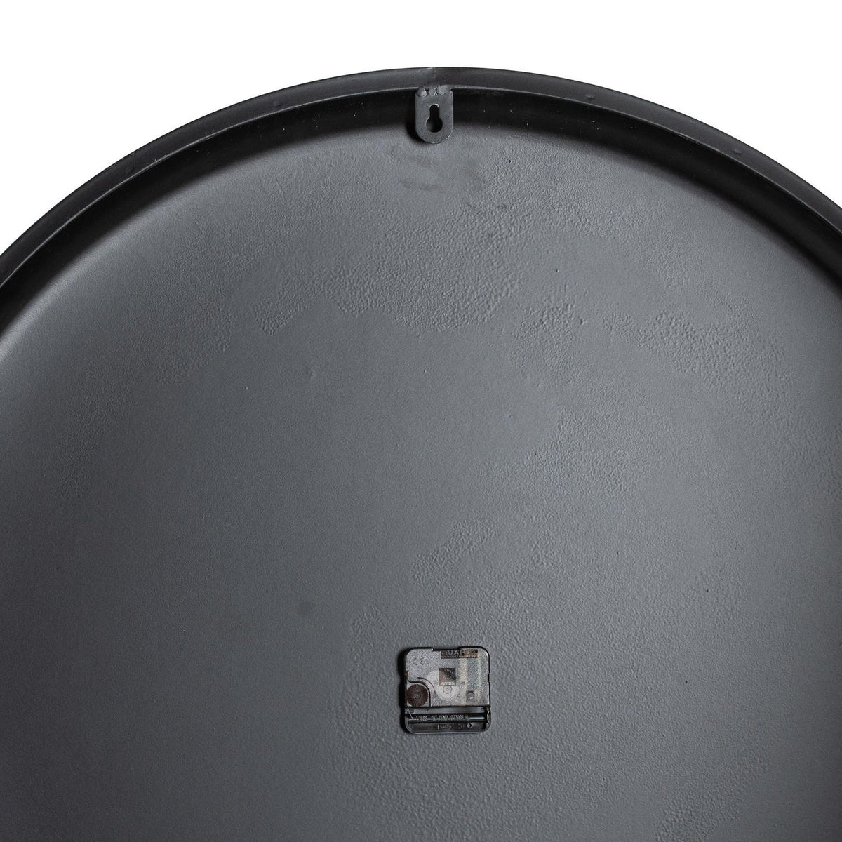 Rear view of the clock showing its dark circular back, small central movement and keyhole-shaped hanging tab near the top rim.