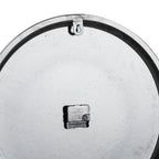 Rear view of the wall clock showing its pale textured back, black clock movement and keyhole-shaped hanging tab beneath the upper rim.