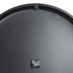 Rear view of the clock showing its dark circular back, a keyhole hanging tab at the top and the movement near the lower centre.