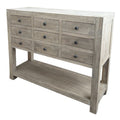 Three-quarter view of a pale grey-brown chest with nine drawers, dark drawer hardware, broad corner posts and an open lower shelf against a white background.