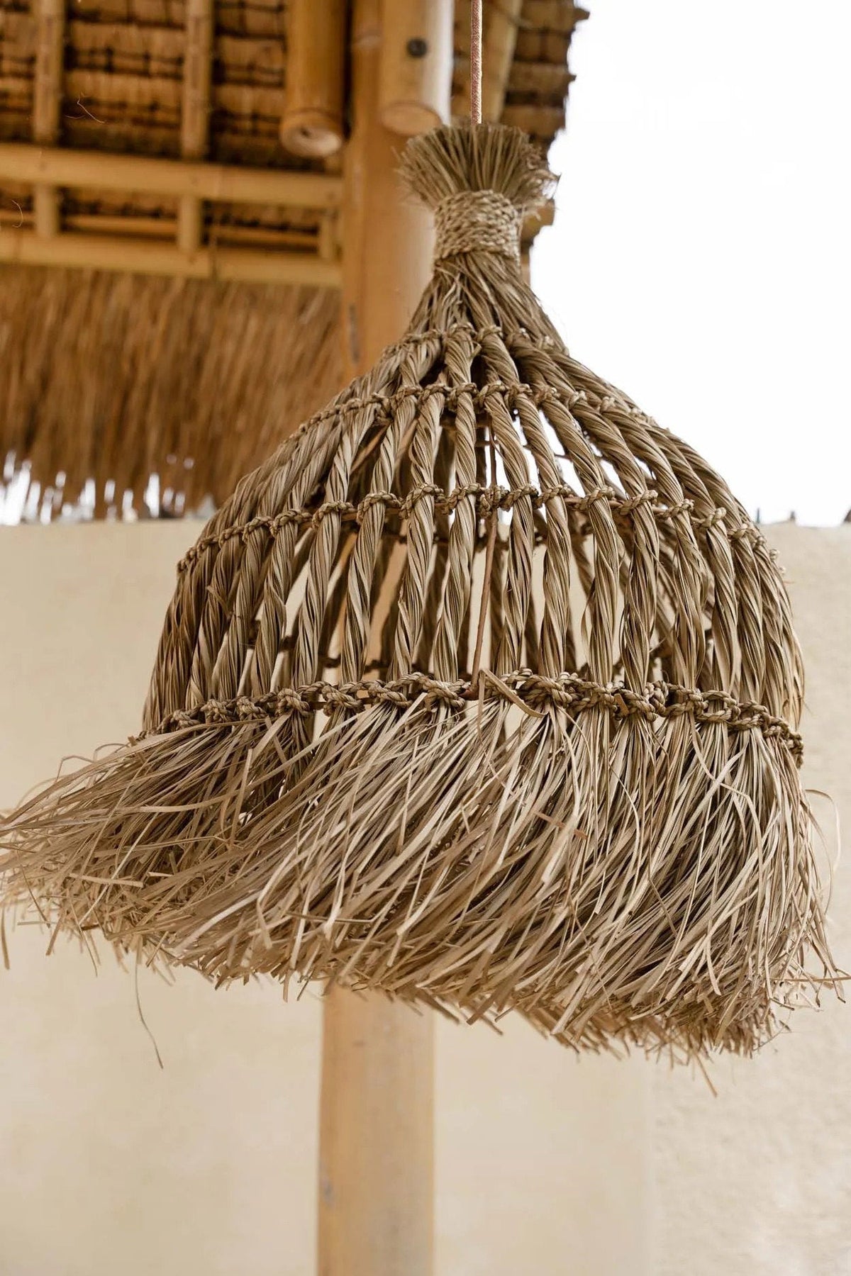 Guagua Mendong Grass Pendant Light – Natural, Large – close hanging view beneath a thatched roof