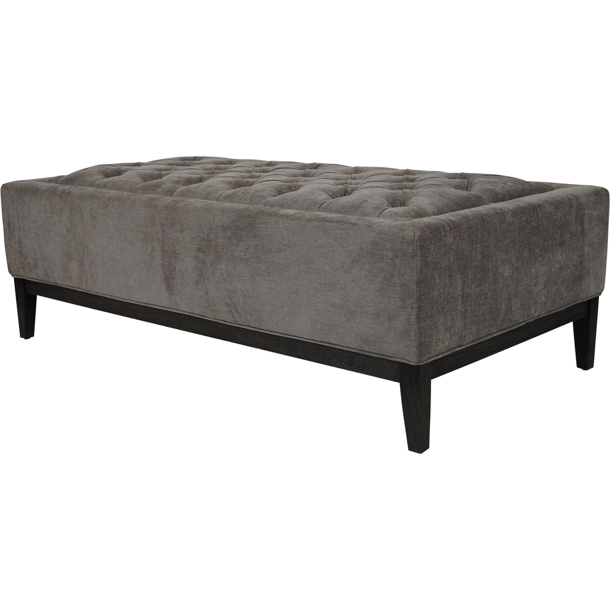 Angled view of the ottoman showing the deep upholstered body, tufted top and deep-brown wooden rails with tapered legs.