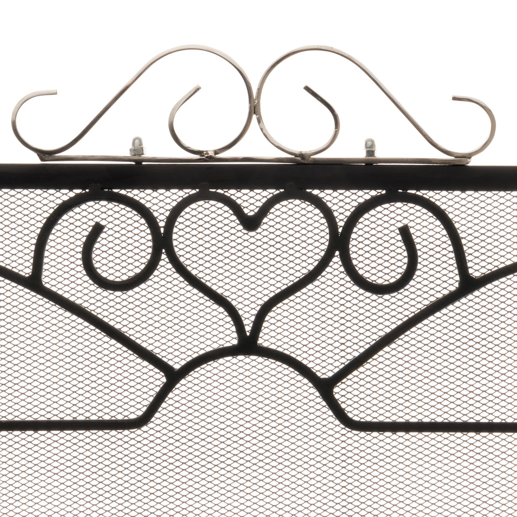 Close-up of the fire screen's silver-toned scroll crest above a black heart motif and fine diamond-patterned mesh.