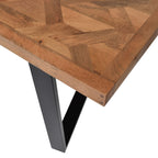 Close-up of a tabletop corner showing the herringbone inlay, varied wood grain and straight wooden border above a black leg.