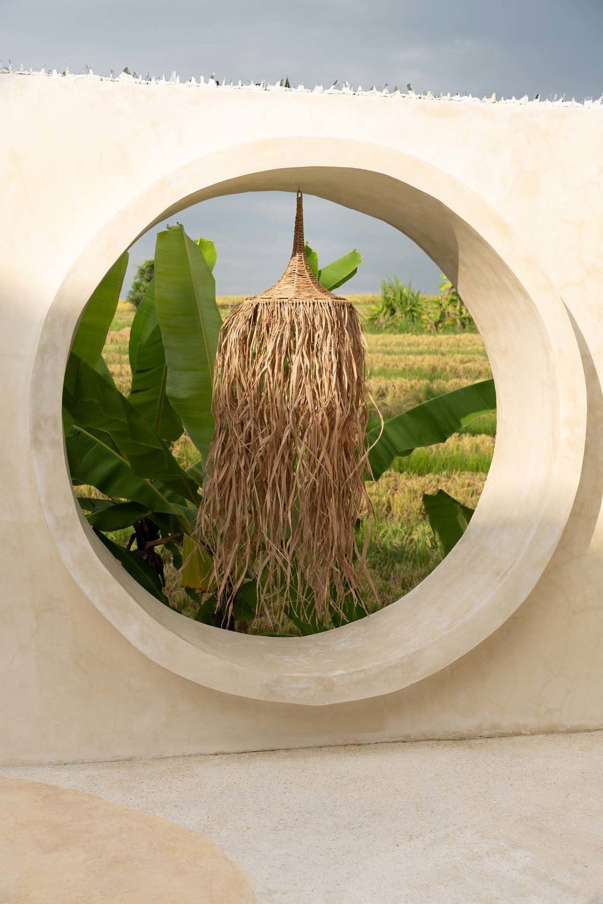 Honolulu Raffia Pendant Light – Natural — styled beside a round mirror