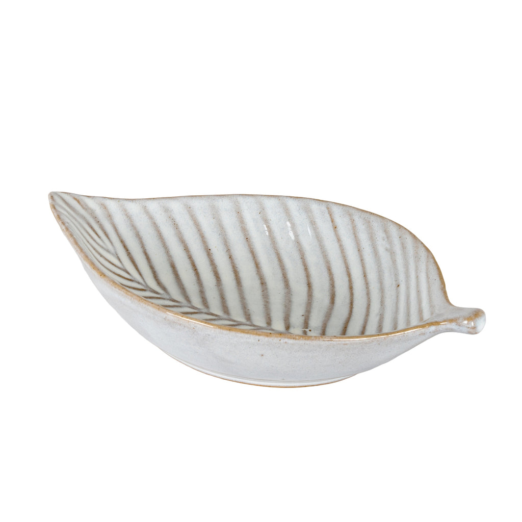 Angled view of the off-white leaf-shaped dish, showing its curved sides, pointed left tip and short stem on the right.