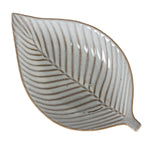 Close overhead view of the leaf-shaped dish, with brown-grey veins branching from the central midrib across the speckled off-white interior.