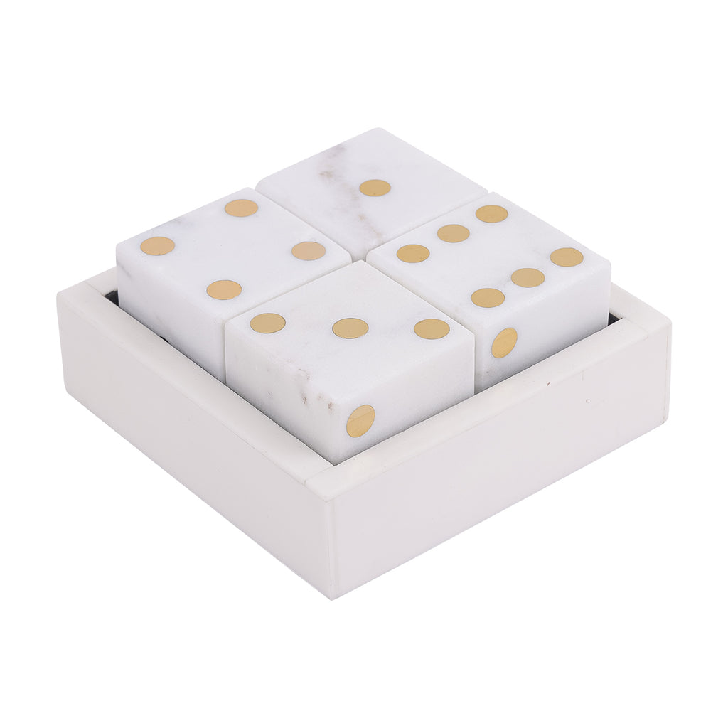 Angled view of four white marble dice with brass-coloured pips arranged in a square marble box.