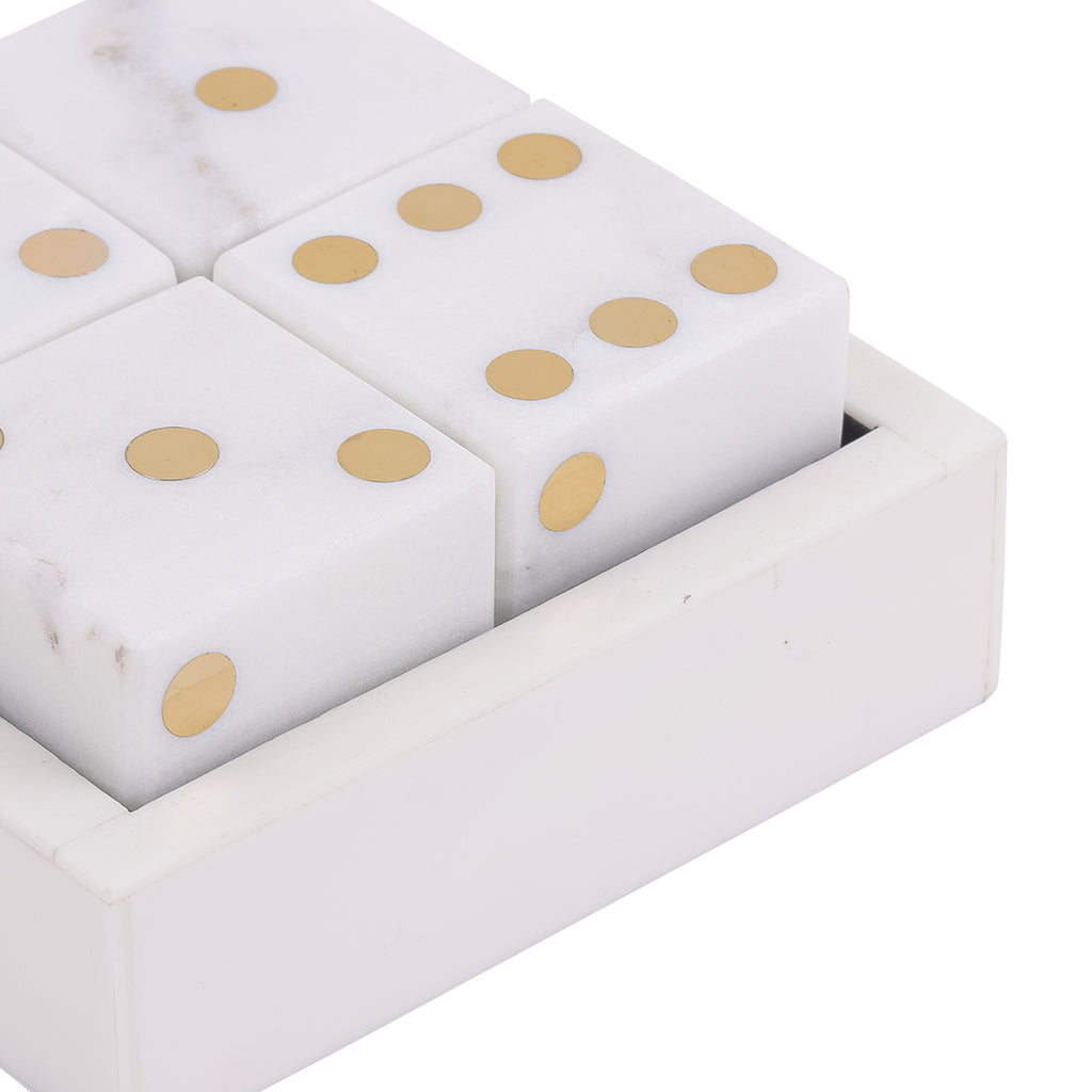 Close-up of brass-coloured pips and subtle veining on white marble dice inside the marble box.