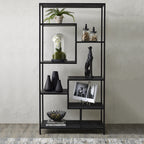 Black shelving unit against a pale textured wall, styled with a fern, glass jars, flowers under a glass dome, black vases, an animal sculpture and an open book.