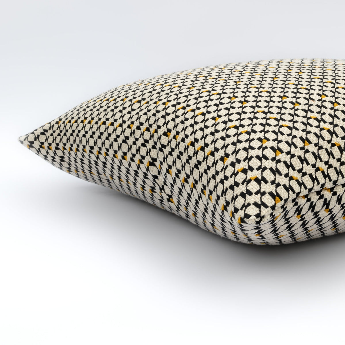 Angled view of the Ivara Cushion showing its black, cream and amber geometric pattern