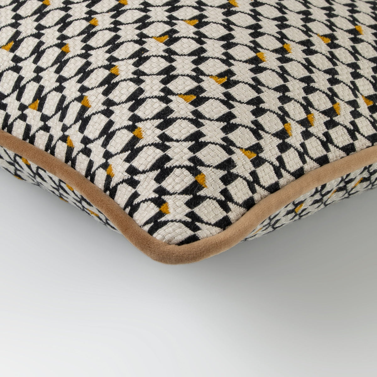 Angled view of the Ivara Cushion with amber piping and geometric fabric