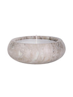 Side view of the beige marble candle, showing its curved body, natural markings and wax below the rounded rim.