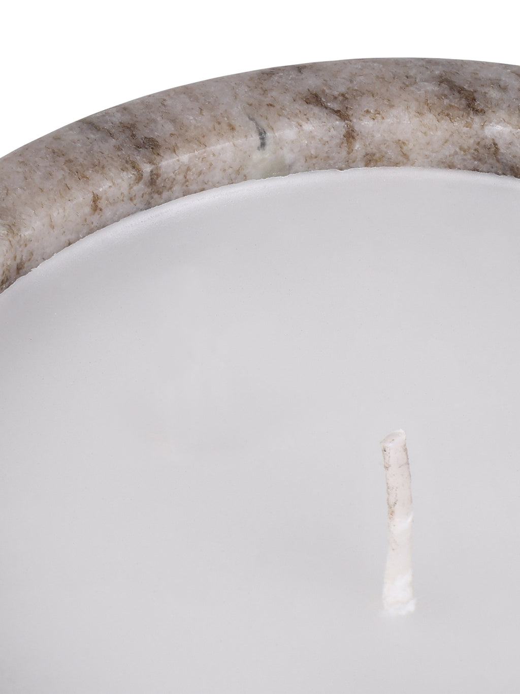 Close-up of the candle's white wax and unlit wick beside the beige marble rim with brown and grey mineral markings.