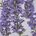 Close-up of lavender-purple artificial flowers with overlapping curved petals along slender green stems.