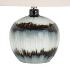 Close view of the rounded lamp base, showing glossy reflections, feathered dark bands and vertical streaks through pale grey-white areas.