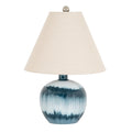 Blue table lamp with a rounded banded base, broad off-white tapered shade and grey ball finial on a white background