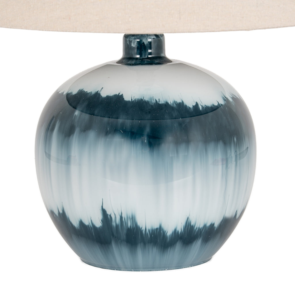 Close-up of the glossy rounded lamp base showing feathered dark teal bands and pale vertical blue streaks beneath the shade