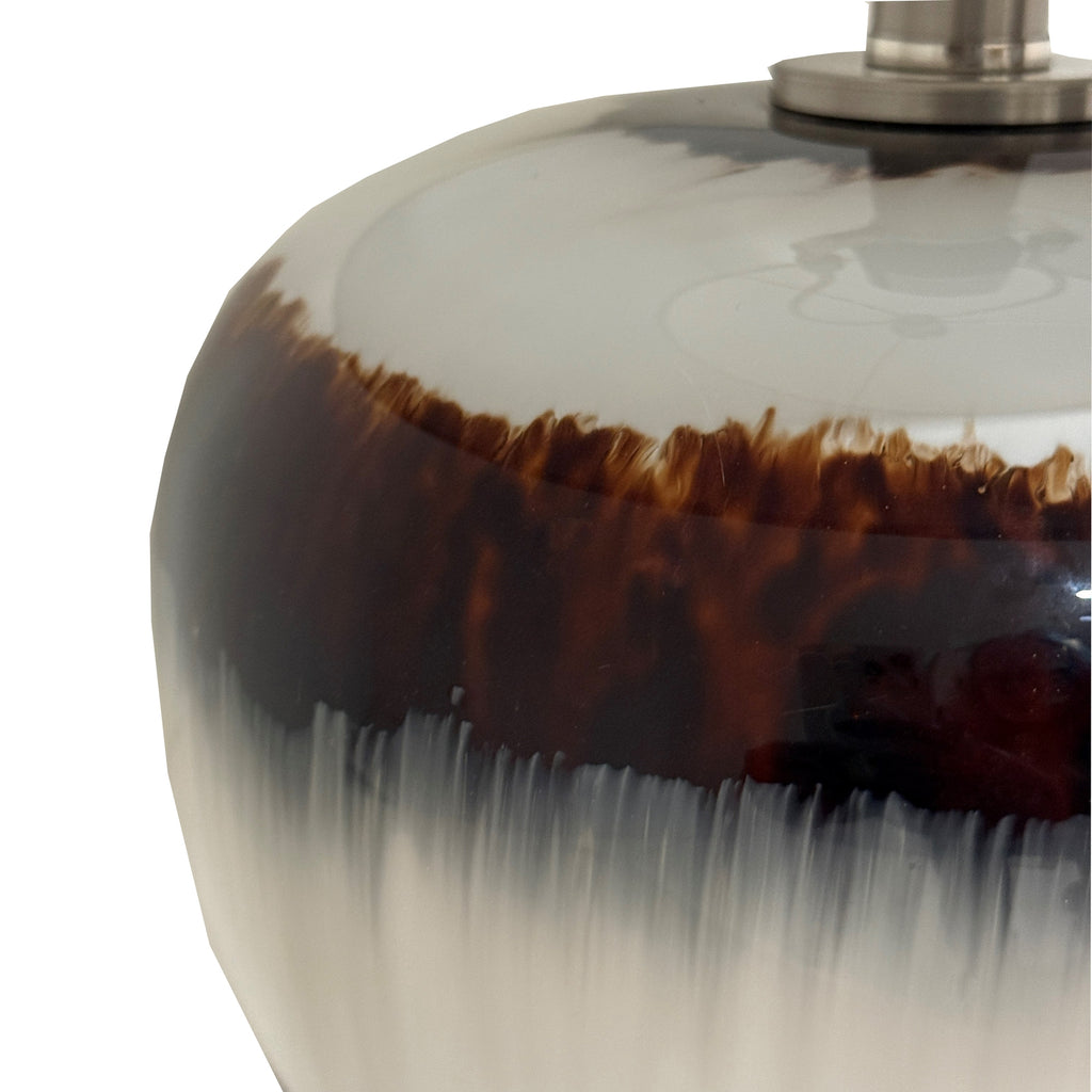 Close-up of the glossy lamp base showing a deep brown band with feathered amber edges and vertical streaks through the pale grey-beige finish
