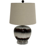 Table lamp with a broad beige shade, dark spherical finial and glossy rounded base patterned with brown bands on a clear stepped foot