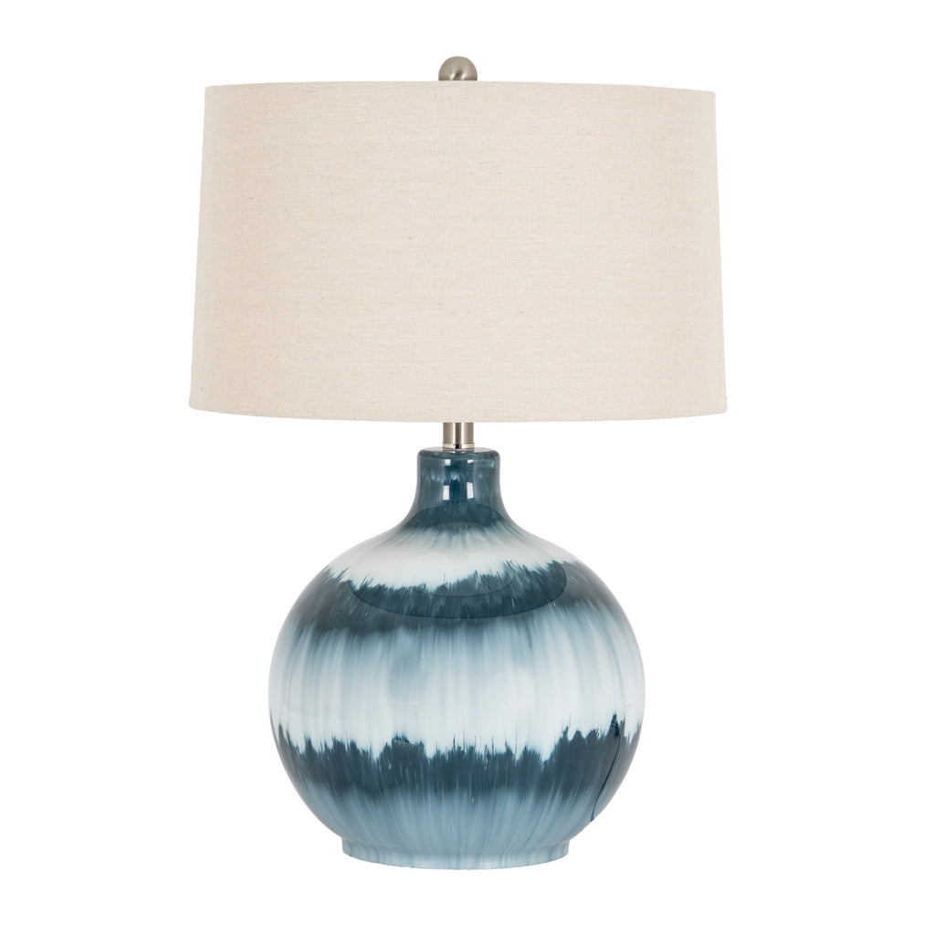 Blue table lamp with a rounded banded body, broad off-white drum shade and small grey ball finial against a white background.