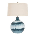 Blue table lamp with a rounded banded body, broad off-white drum shade and small grey ball finial against a white background.