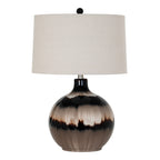 Table lamp on white with a glossy rounded taupe, cream and near-black banded body, pale tapered shade and dark ball finial.