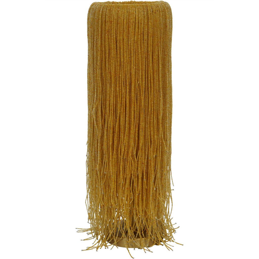Full view of a tall table lamp covered in amber bead strands, with loose fringe around its round gold-coloured base.
