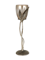 Leaf Stem Hurricane candle holder with warm-toned glass, two sculpted leaves and a twisting gold-coloured stem on a round base.