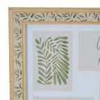 Close-up of the frame's upper left corner, showing the green leaf print on a textile-like pale band between two wood-tone trims and a botanical insert within the white mount.
