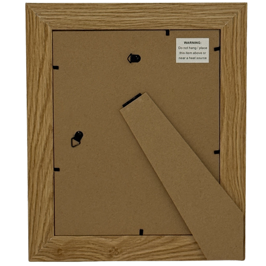 Rear view of the photo frame showing a brown back panel, fold-out stand, two hanging loops and a product label warning against placement above or near a heat source.