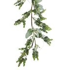 Close-up of rounded green leaf clusters and broad pale leaves along brown garland stems, with a fine clear light wire visible between them.