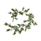 Artificial foliage garland curved against a white background, with mixed green leaves, small glowing light points and a visible battery box.